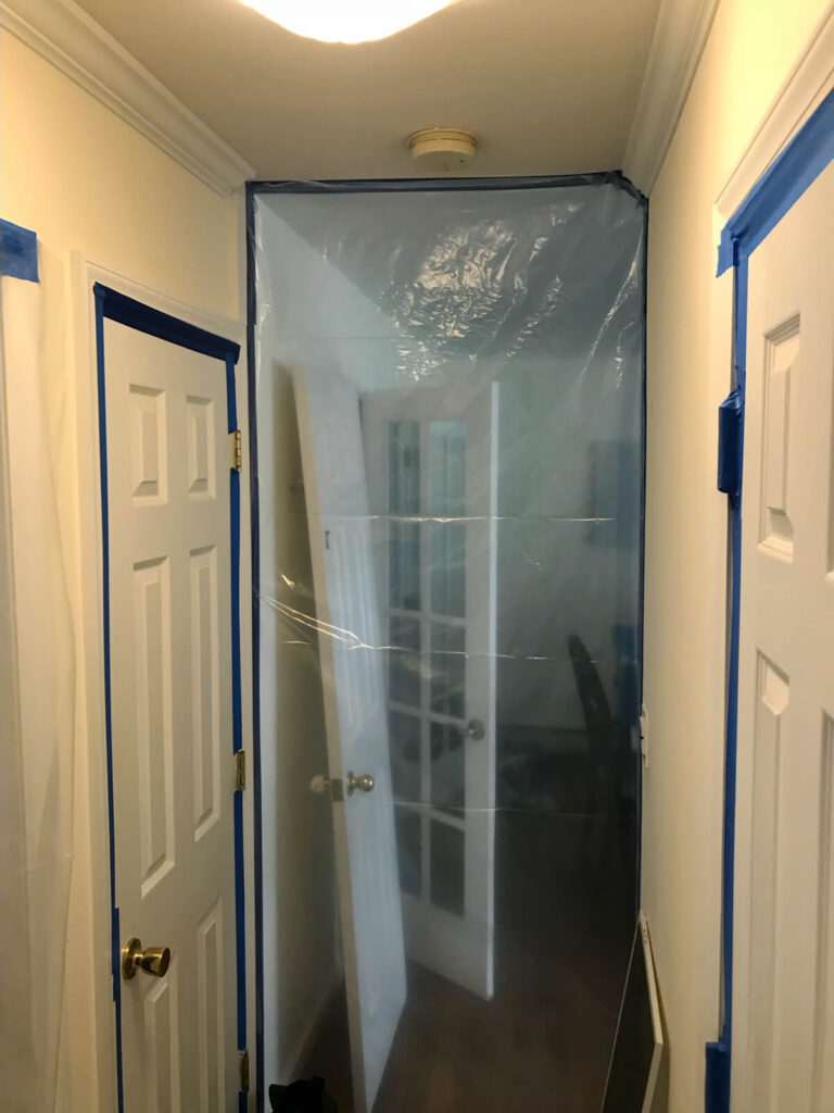 A Bathroom Door Covered In Plastic, Indicating Biohazard Cleanup.