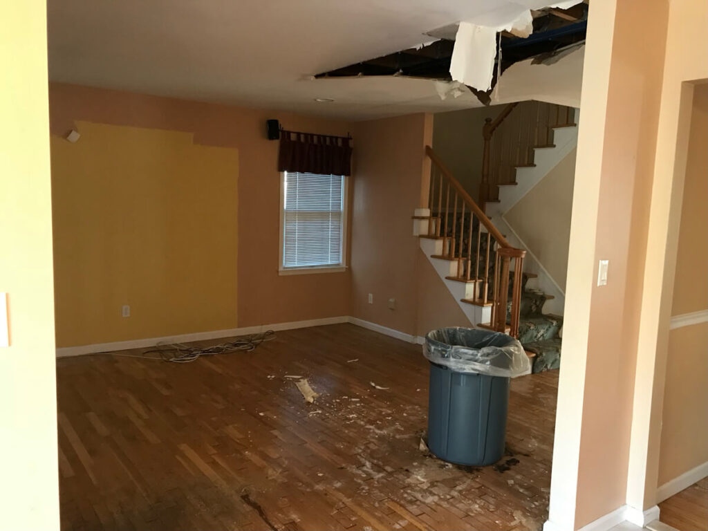 A Room With A Damaged Ceiling And A Trash Can, Showing Signs Of Water Leakage
