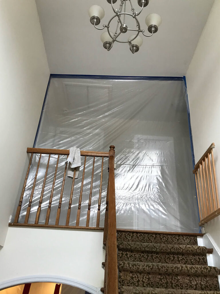 Biohazard Cleanup Zone: A Stairway Covered In Plastic With A Light Fixture Overhead.