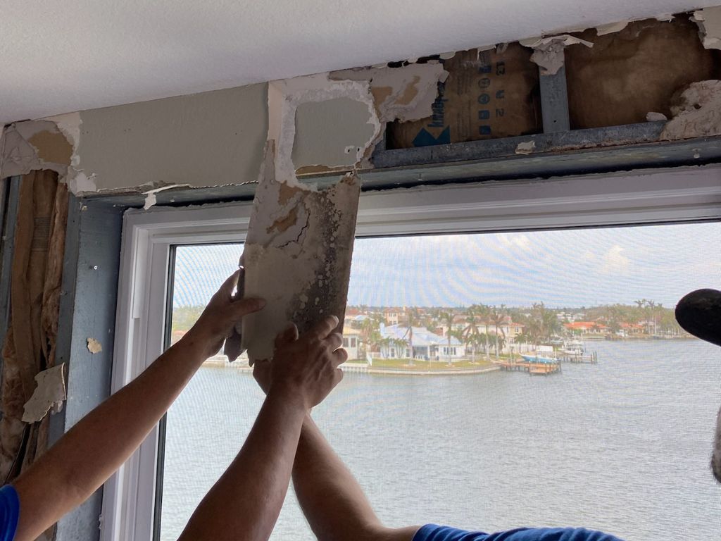 Workers Removing Damaged Drywall Near A Window.