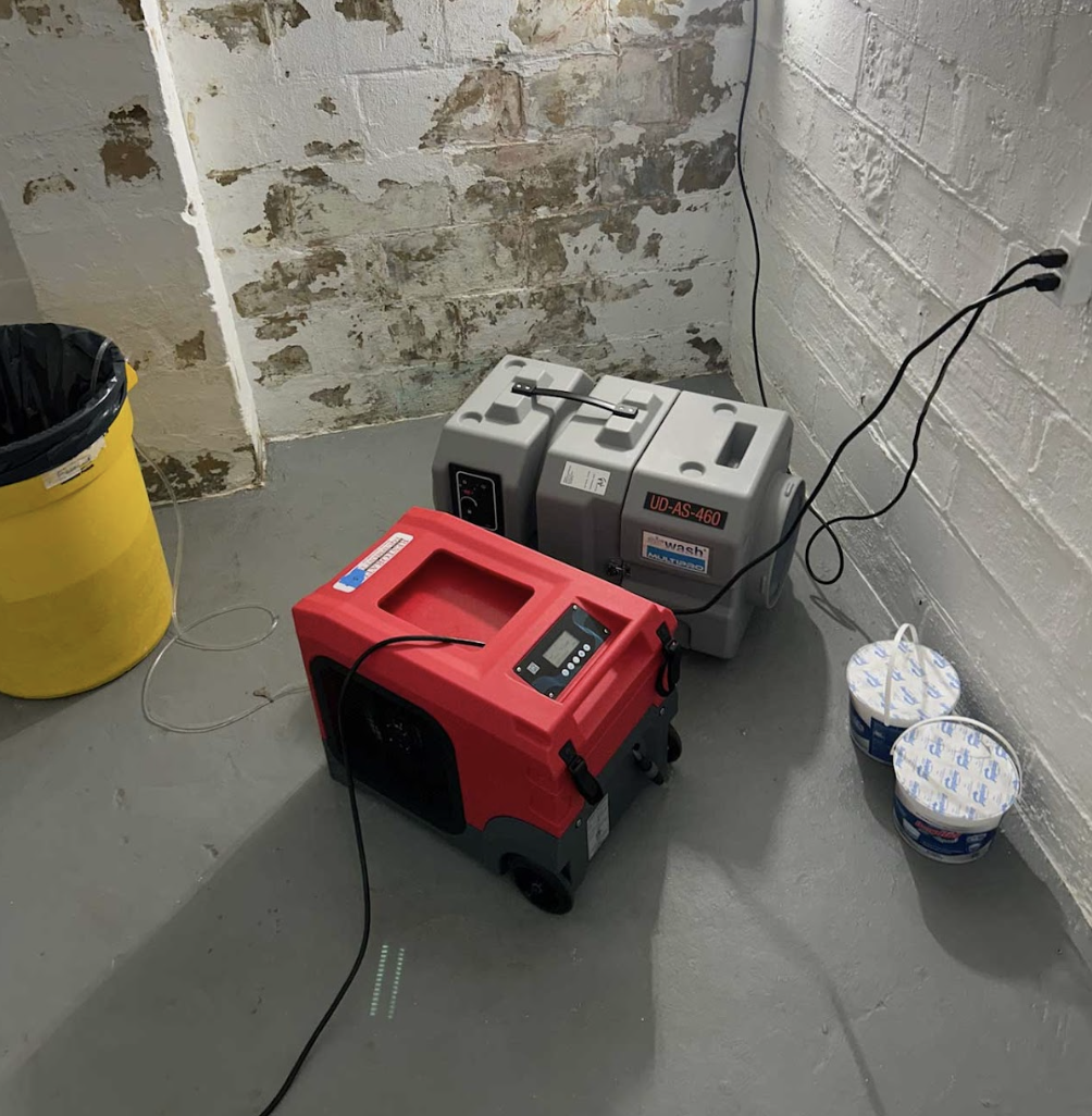 A Portable Generator And A Bucket Of Water Are Placed On The Floor In A Room, Highlighting A Utility Setup.