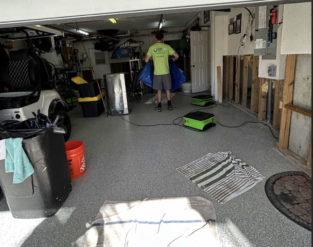 A Man Uses A Vacuum To Clean A Cluttered Garage, Focusing On Removing Dust And Debris From The Floor.
