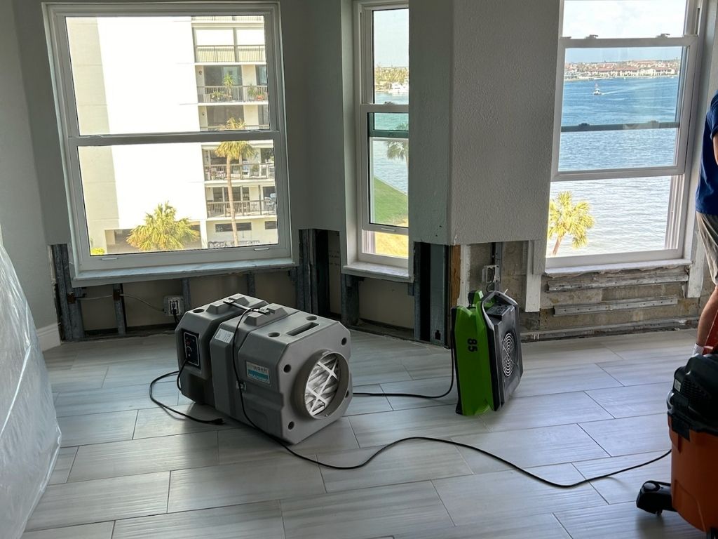 Apartment Undergoing Water Damage Restoration With Drying Equipment And Exposed Walls, Overlooking A Waterfront View.