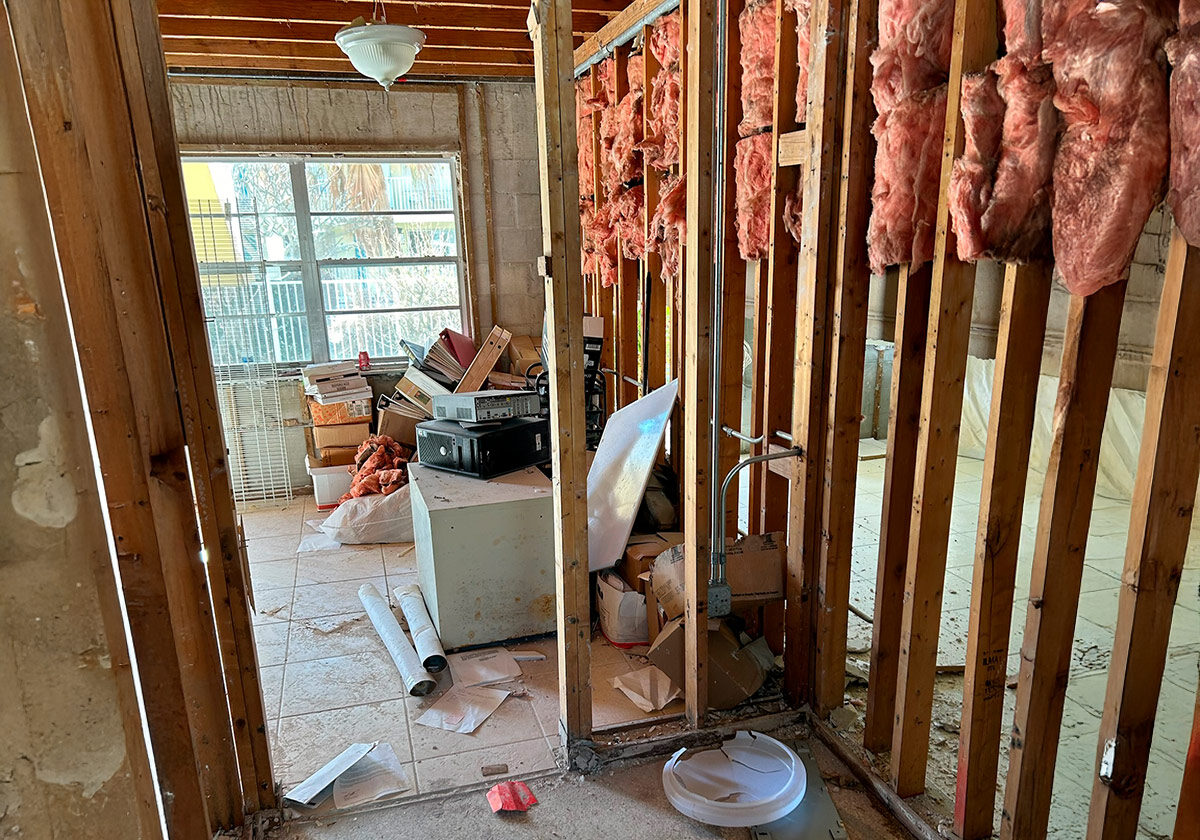 Water,-Fire,-And-Mold-Remediation-Service-Areas23 A Cluttered Room With Exposed Wooden Beams, Insulation Hanging From The Walls, And Piles Of Boxes And Debris Scattered On The Floor.