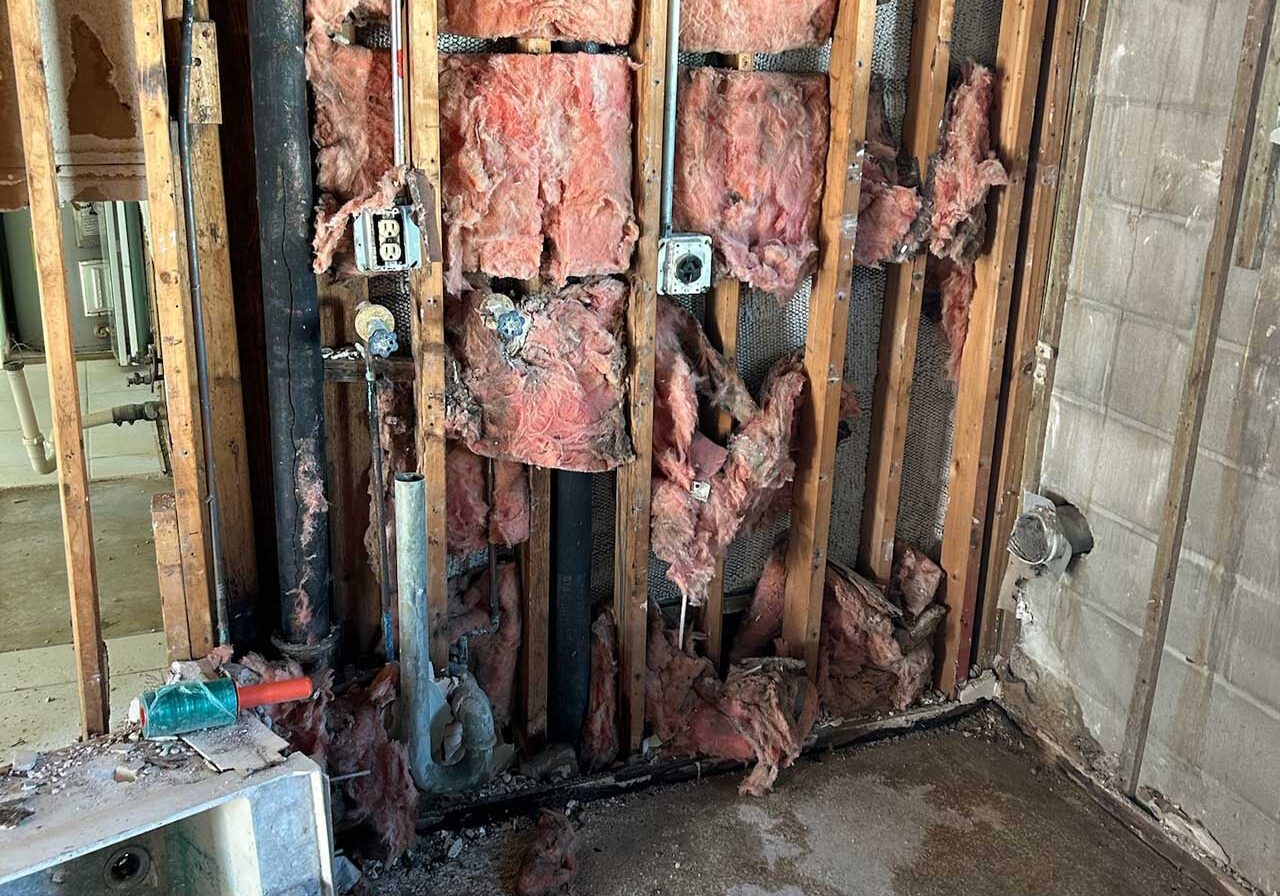 Close-Up Of Severely Water-Damaged Drywall And Exposed, Wet Insulation In A Building Undergoing Disaster Restoration.