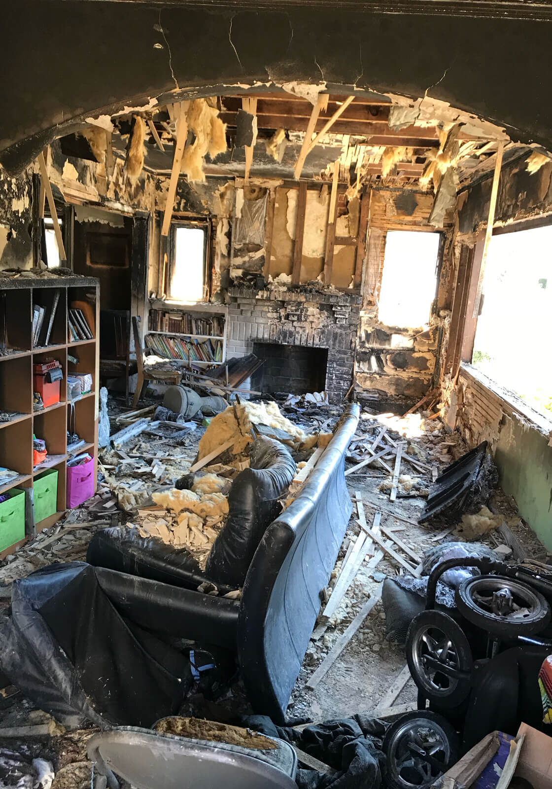 A Charred Interior Of A House, Ravaged By Fire, With Blackened Walls, Melted Furniture, And Debris Scattered Across The Floor