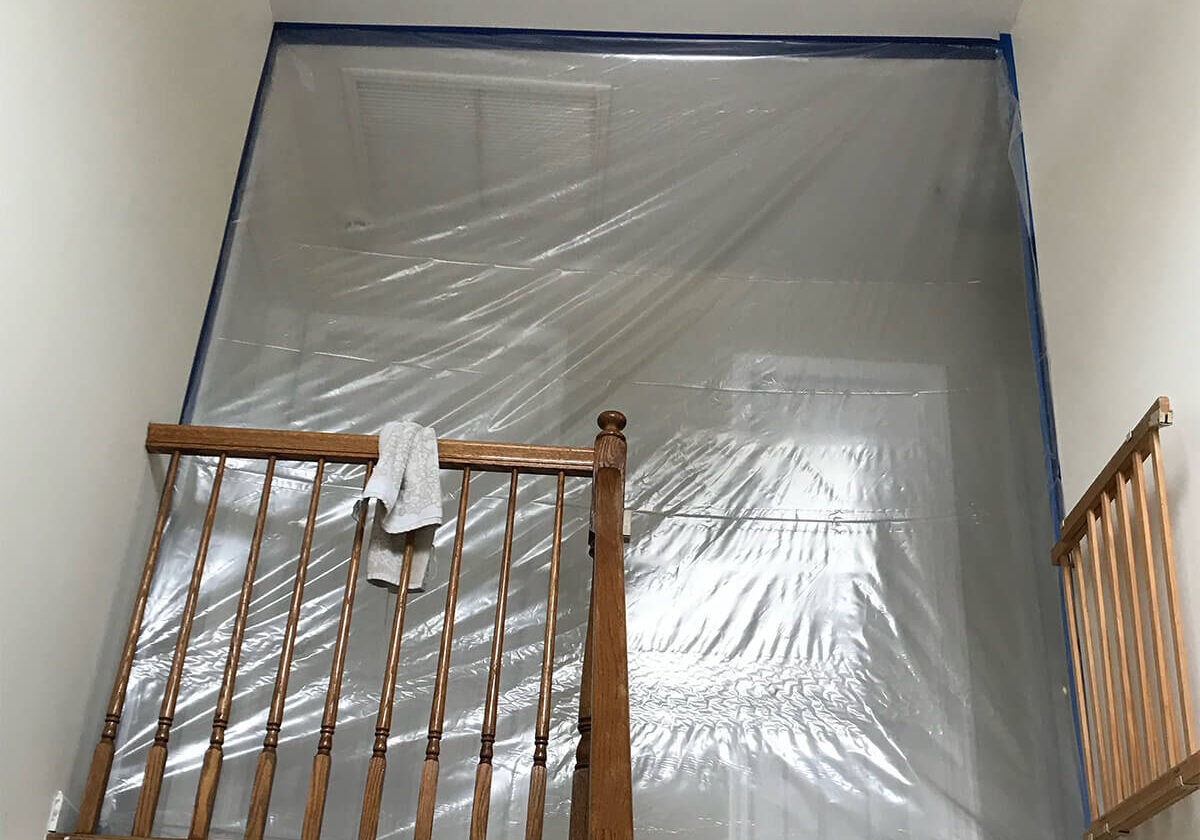 Stairway-Covered Biohazard Cleanup Zone: A Stairway Covered In Plastic With A Light Fixture Overhead.